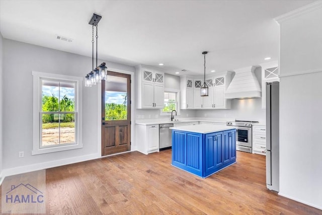 kitchen with premium range hood, appliances with stainless steel finishes, white cabinets, light countertops, and blue cabinets