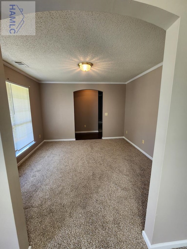 carpeted empty room with crown molding, baseboards, and a textured ceiling
