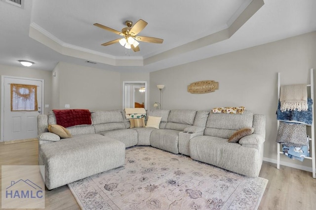 living room with hardwood / wood-style flooring, ceiling fan, crown molding, and a tray ceiling