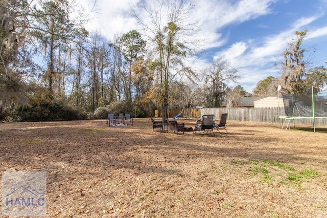 view of yard with a trampoline and a fire pit