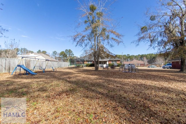 view of yard with a trampoline and a playground