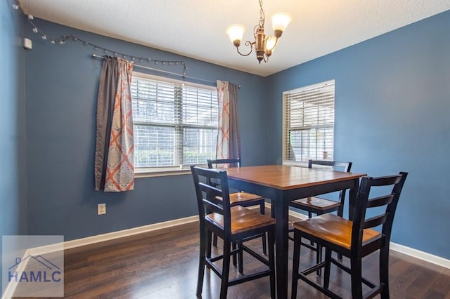 dining room with dark wood-type flooring and an inviting chandelier