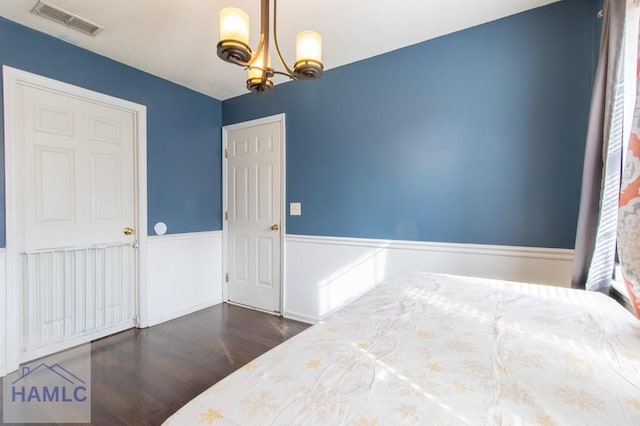 bedroom featuring a notable chandelier and dark wood-type flooring