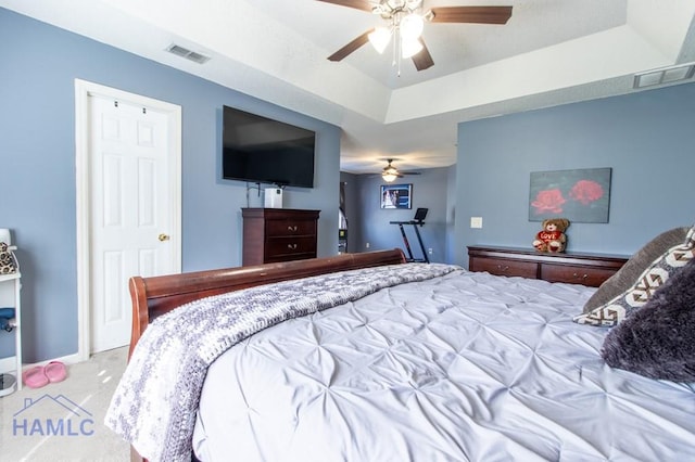 carpeted bedroom featuring ceiling fan and a tray ceiling