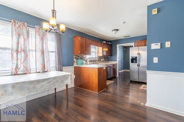 kitchen with appliances with stainless steel finishes, decorative light fixtures, dark hardwood / wood-style floors, and kitchen peninsula