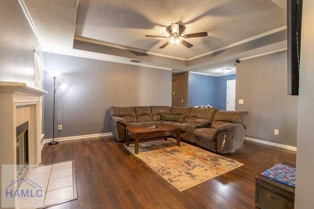 living room with ceiling fan, ornamental molding, a textured ceiling, dark hardwood / wood-style flooring, and a raised ceiling