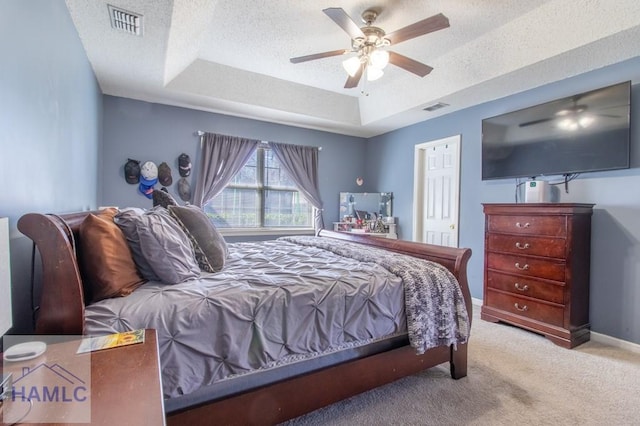 bedroom with ceiling fan, light colored carpet, a raised ceiling, and a textured ceiling