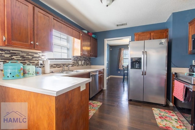 kitchen featuring sink, appliances with stainless steel finishes, dark hardwood / wood-style flooring, kitchen peninsula, and decorative backsplash