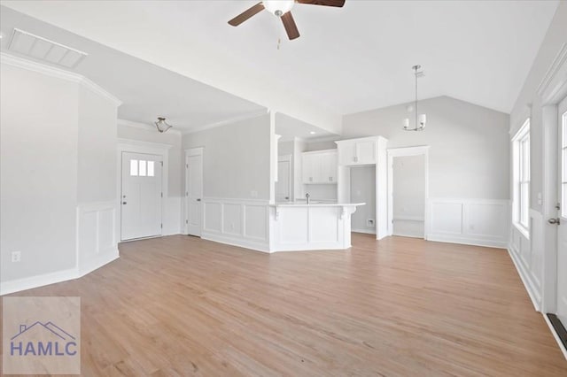 unfurnished living room featuring visible vents, ceiling fan with notable chandelier, light wood-style floors, crown molding, and vaulted ceiling