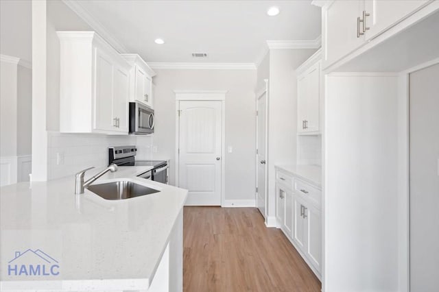 kitchen with light wood finished floors, a sink, white cabinets, appliances with stainless steel finishes, and crown molding