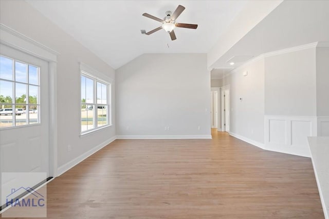 empty room featuring light wood-style flooring, baseboards, a decorative wall, lofted ceiling, and ceiling fan