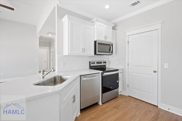 kitchen with visible vents, light wood-style flooring, white cabinets, stainless steel appliances, and a sink