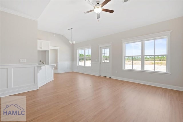 unfurnished living room with a decorative wall, ceiling fan with notable chandelier, light wood-style flooring, and vaulted ceiling