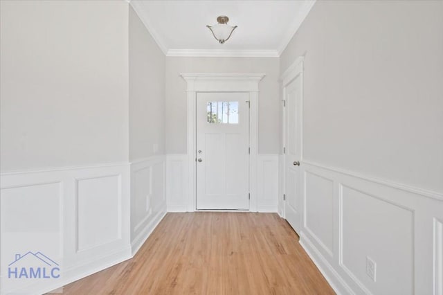 entryway with light wood-style flooring, a wainscoted wall, and ornamental molding