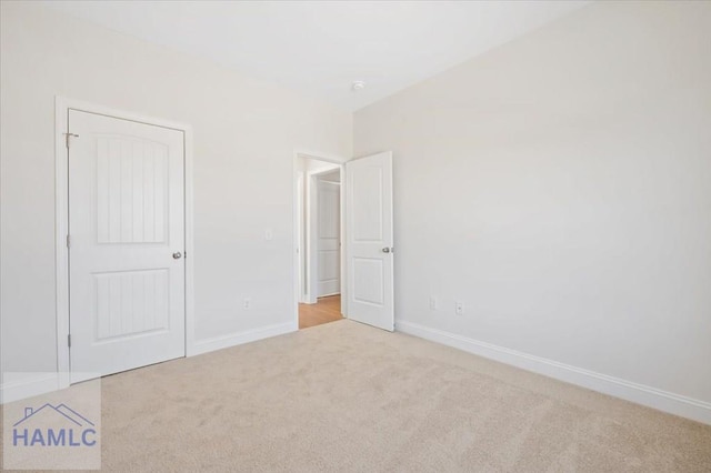 unfurnished bedroom featuring baseboards, light carpet, and a closet