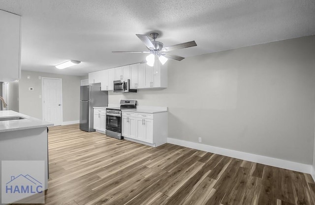 123 2nd Ave, Midway, GA 31313 - kitchen featuring appliances with stainless steel finishes, light countertops, white cabinetry, light wood finished floors, and a textured ceiling