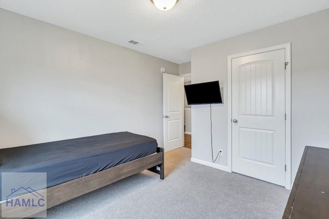 carpeted bedroom with visible vents and a textured ceiling