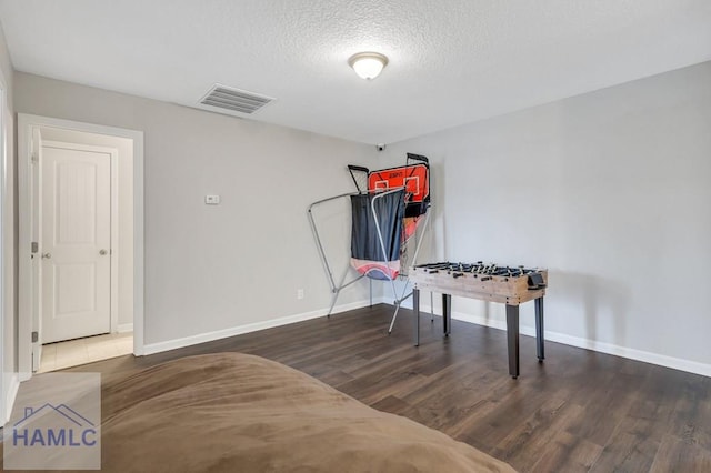 misc room with visible vents, a textured ceiling, baseboards, and wood finished floors