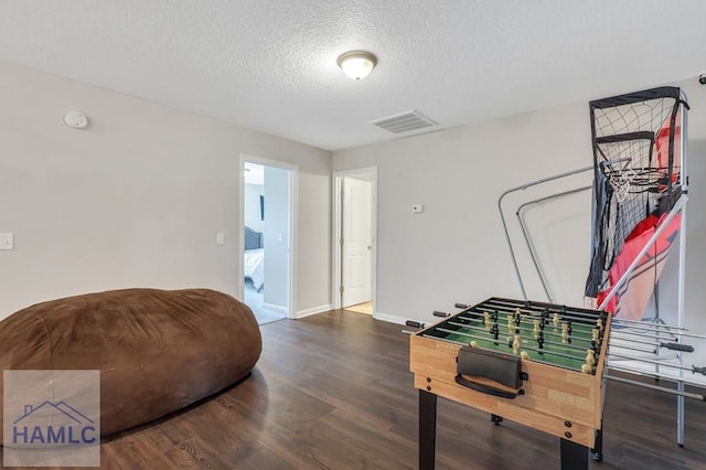 game room with visible vents, a textured ceiling, baseboards, and wood finished floors