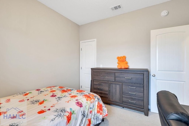 bedroom featuring visible vents and light colored carpet