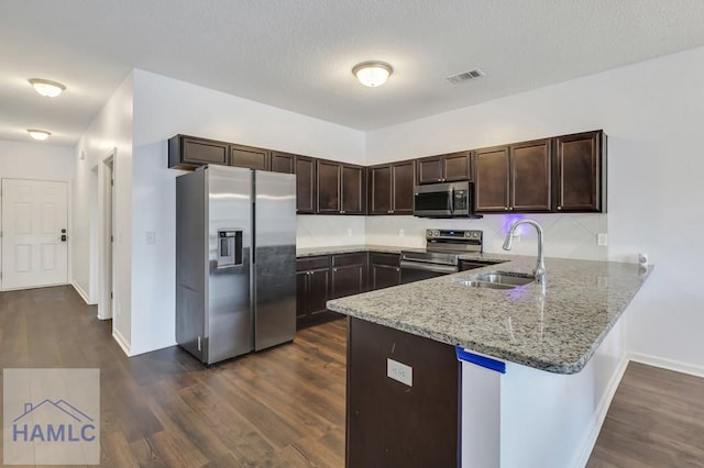 kitchen with visible vents, dark brown cabinets, appliances with stainless steel finishes, a peninsula, and a sink