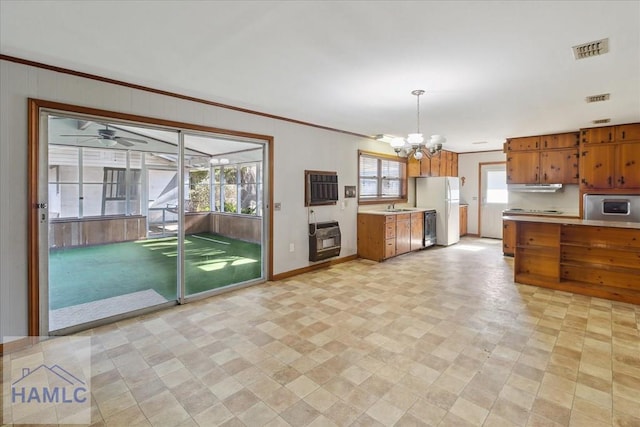 kitchen featuring heating unit, sink, hanging light fixtures, ornamental molding, and white refrigerator