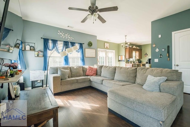 living room with ceiling fan with notable chandelier and dark hardwood / wood-style floors