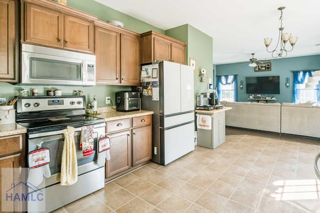 kitchen with ceiling fan with notable chandelier, stainless steel appliances, and decorative light fixtures