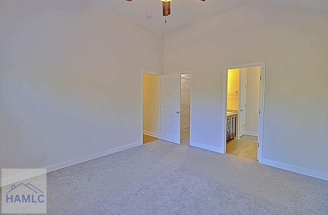 unfurnished bedroom featuring a spacious closet, light colored carpet, a closet, a towering ceiling, and ceiling fan