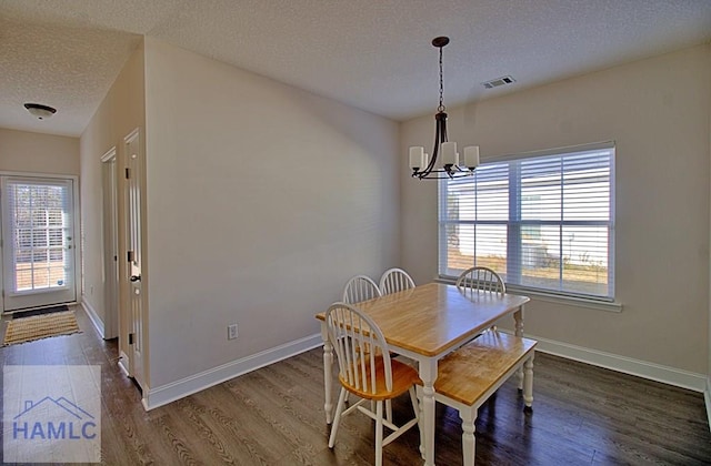 dining space with a textured ceiling, dark hardwood / wood-style floors, an inviting chandelier, and a healthy amount of sunlight