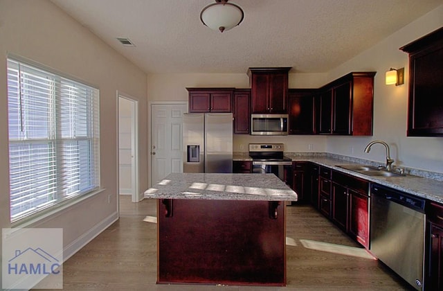 kitchen with stainless steel appliances, light hardwood / wood-style floors, sink, and a kitchen island