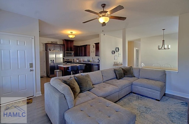 living room featuring ceiling fan with notable chandelier and light hardwood / wood-style flooring