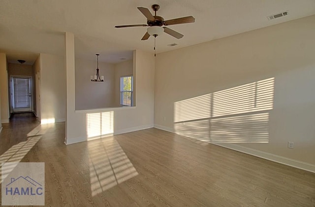 unfurnished living room with wood-type flooring and ceiling fan with notable chandelier