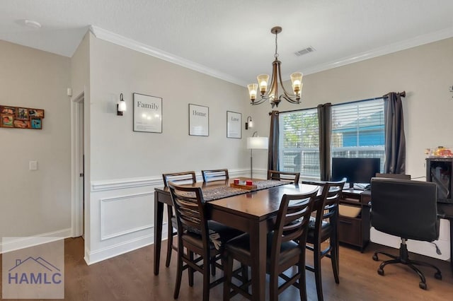 dining room with dark hardwood / wood-style floors, ornamental molding, and a notable chandelier