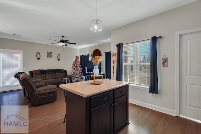 kitchen with pendant lighting, dark hardwood / wood-style floors, a center island, and ceiling fan