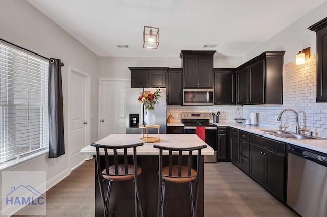 kitchen featuring pendant lighting, sink, a kitchen island, light hardwood / wood-style floors, and stainless steel appliances