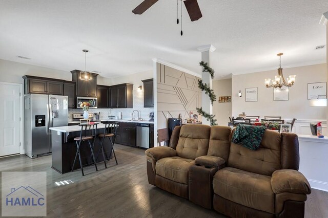 living room with hardwood / wood-style floors, ceiling fan with notable chandelier, ornamental molding, and sink