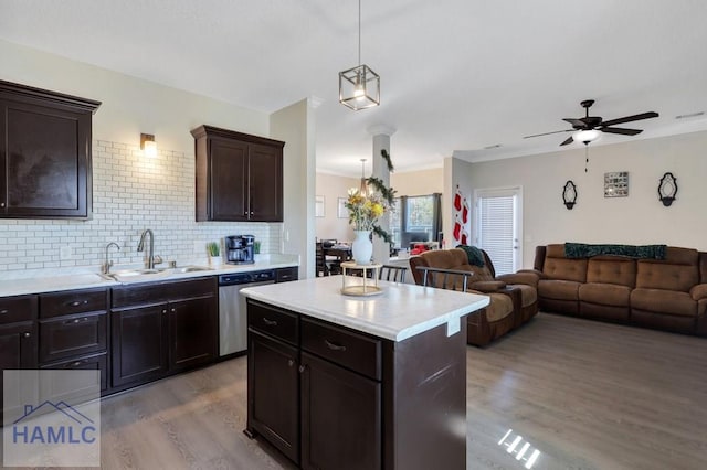 kitchen featuring sink, hanging light fixtures, light hardwood / wood-style flooring, stainless steel dishwasher, and a kitchen island