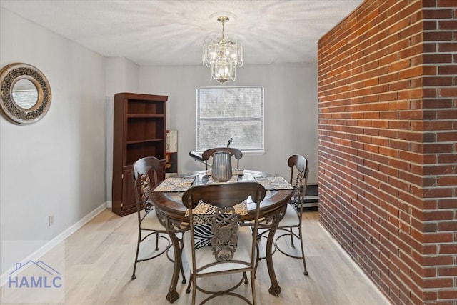 dining area featuring light wood-type flooring, brick wall, and an inviting chandelier