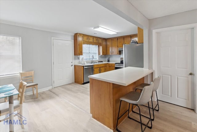 kitchen featuring a kitchen breakfast bar, light wood-type flooring, stainless steel appliances, and sink