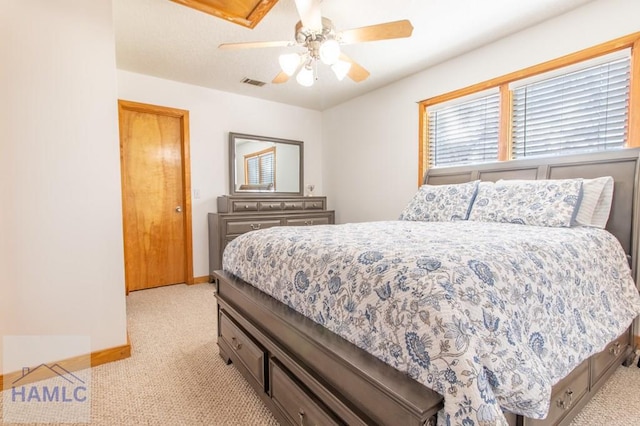 bedroom featuring a ceiling fan, visible vents, light carpet, and baseboards