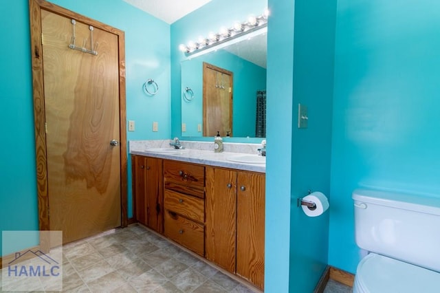 bathroom with toilet, double vanity, and a sink