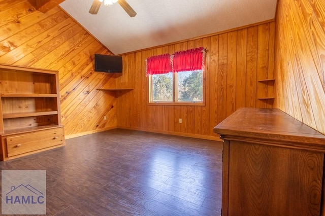 bonus room featuring dark wood-type flooring, a ceiling fan, vaulted ceiling, wood walls, and baseboards