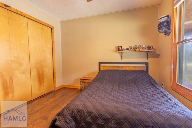 bedroom featuring a textured ceiling, wood finished floors, and baseboards