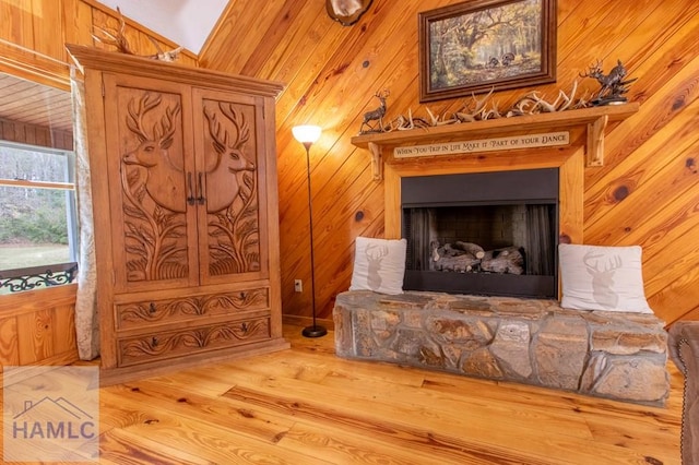 living area featuring wood walls, a skylight, a fireplace with raised hearth, and wood finished floors