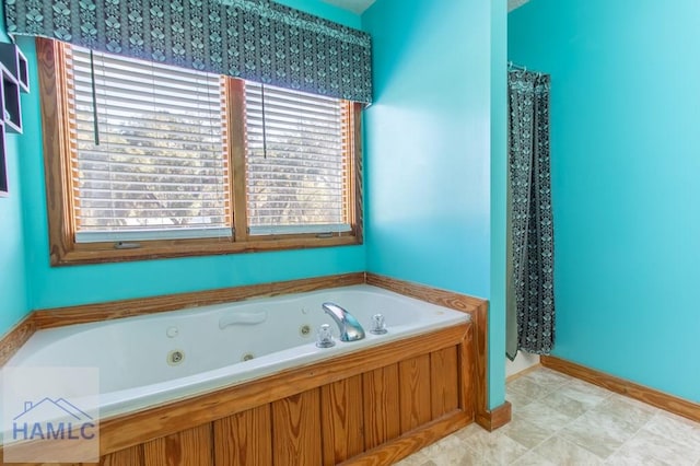 full bath featuring a whirlpool tub and baseboards