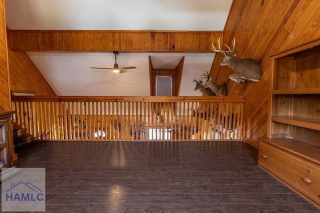 interior space featuring wood walls, ceiling fan, vaulted ceiling, and dark wood-type flooring