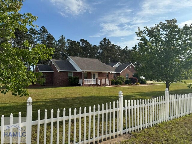 21 Forest Rd, Odum, GA 31555 - ranch-style house featuring covered porch, a fenced front yard, a front lawn, and brick siding