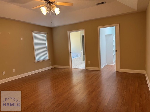 21 Forest Rd, Odum, GA 31555 - empty room with ceiling fan, visible vents, baseboards, a tray ceiling, and dark wood-type flooring