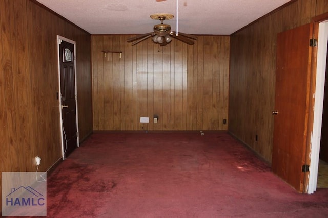 carpeted empty room with ceiling fan and wood walls